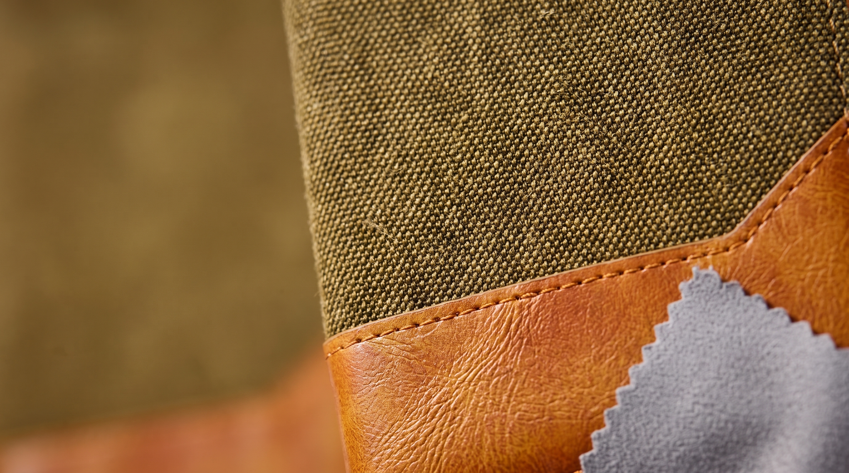 Macro close-up of a Walnut denim wallet flip cover: woven denim meeting the tan vegan-leather trim, with a microfibre cleaning cloth