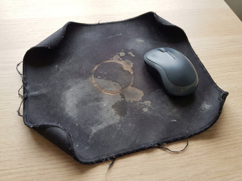 Old rectangular cloth mouse pad with curled corners, frayed edge and a chai stain
